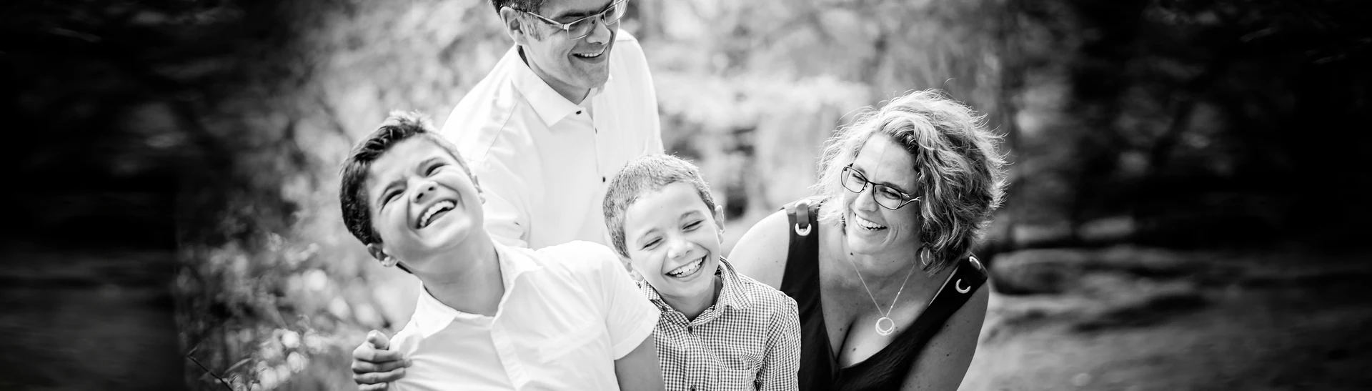 Famille de quatre riant ensemble au bord de l'eau, en noir et blanc